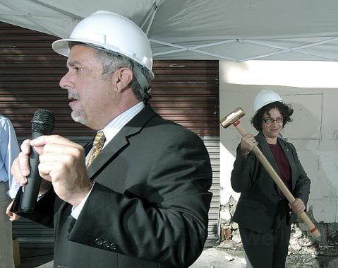 <strong>Razing and raising:</strong>  Mayor Helene Schneider takes a ceremonial swing at the building that used to house Haagen Printing. In its place will go 55 new studio apartments whose rents will range from $408-$800 per month.
