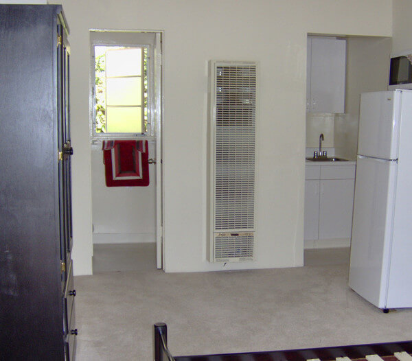 Inside a unit, view of a room with a fridge and cabinet