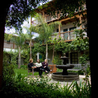 Outside view of three women sitting on the bench in front of the water fountain, talking