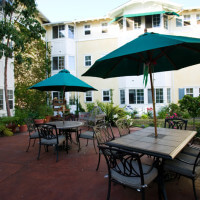Outside shot of chairs and tables with umbrellas, with the units in the background