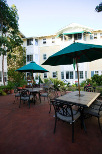 Outside shot of chairs and tables with umbrellas, with the units in the background