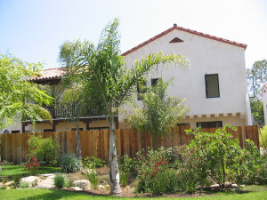 Outside view of a few trees and plants and a unit separated by a fence