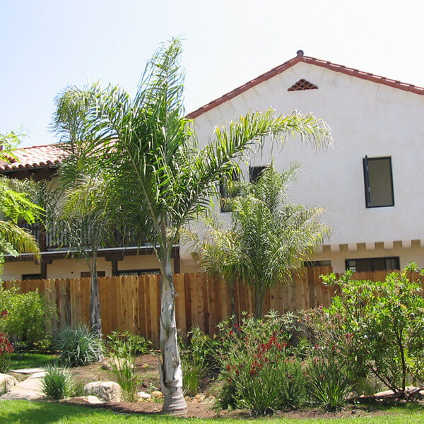 Outside view of a few trees and plants and a unit separated by a fence