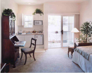 Inside a unit, showing the bedroom with a small desk and kitchenette